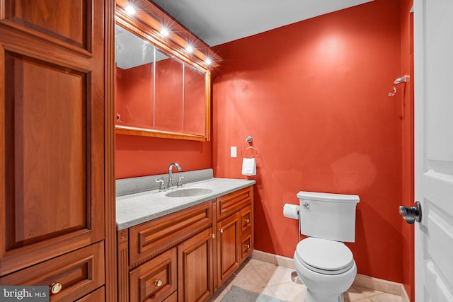 half bathroom featuring tile patterned flooring, toilet, vanity, and baseboards