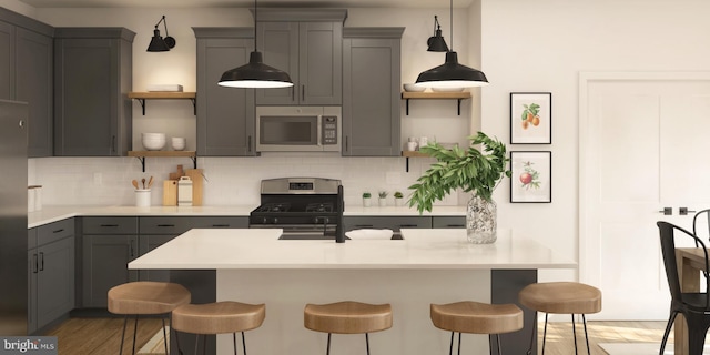 kitchen with backsplash, appliances with stainless steel finishes, gray cabinets, and a breakfast bar