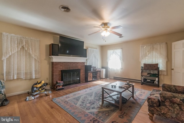 living room featuring hardwood / wood-style flooring, a brick fireplace, ceiling fan, and baseboard heating