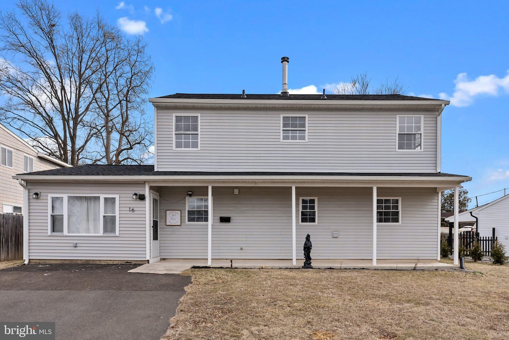 rear view of property featuring a patio, a lawn, and fence