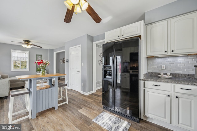 kitchen featuring white cabinets, light wood-type flooring, black refrigerator with ice dispenser, and backsplash