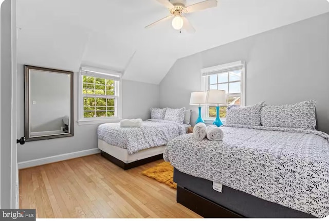 bedroom featuring hardwood / wood-style flooring, ceiling fan, multiple windows, and lofted ceiling