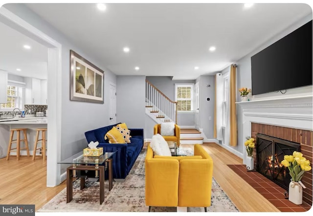 living room with a brick fireplace and hardwood / wood-style flooring