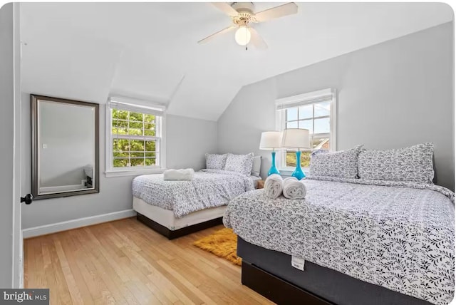 bedroom with multiple windows, vaulted ceiling, ceiling fan, and wood-type flooring