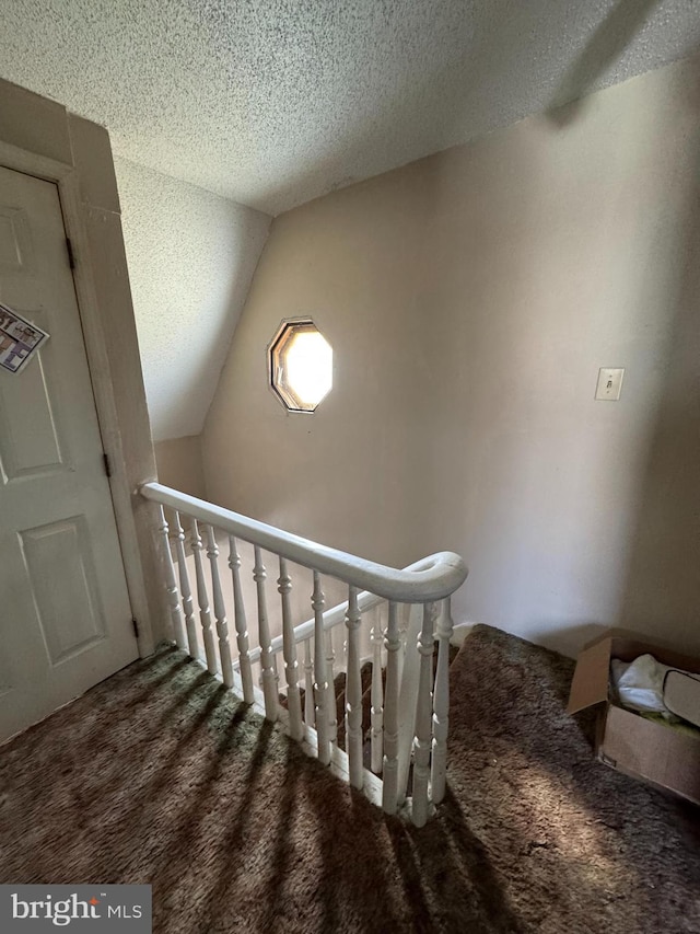 stairs with carpet flooring, a textured ceiling, and lofted ceiling