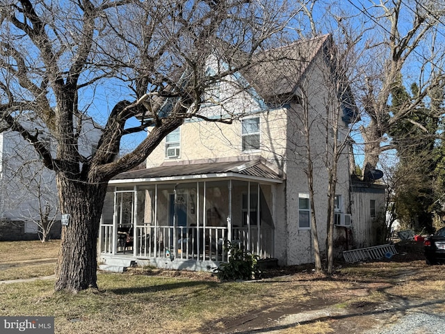 view of front of house featuring cooling unit, a front lawn, and a sunroom