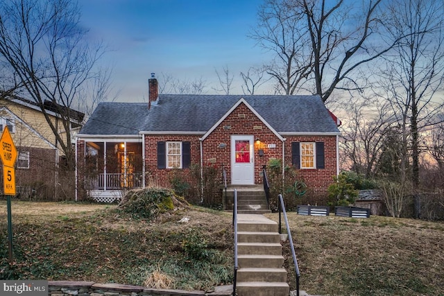 view of front facade with roof with shingles, a chimney, and brick siding