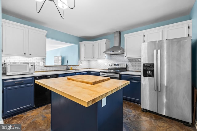 kitchen featuring wall chimney range hood, blue cabinetry, stainless steel appliances, and a kitchen island