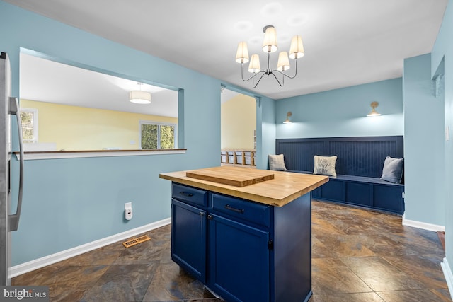 kitchen featuring a chandelier, a center island, blue cabinetry, butcher block countertops, and hanging light fixtures