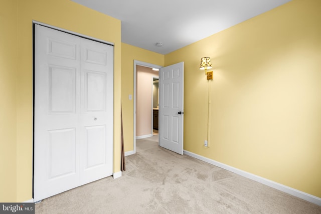 unfurnished bedroom with light carpet and a closet