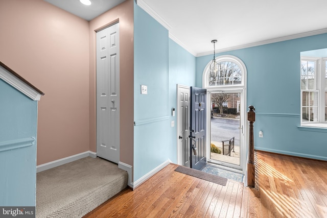 entryway featuring a notable chandelier, ornamental molding, and hardwood / wood-style floors