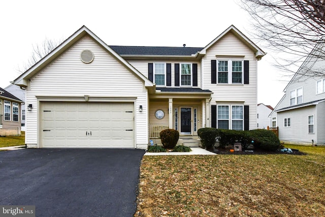 traditional-style home with a garage, aphalt driveway, and a front yard