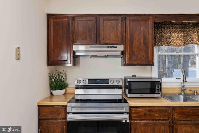 kitchen featuring stainless steel appliances, light countertops, a sink, and under cabinet range hood