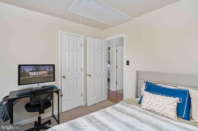 bedroom with attic access, light carpet, and baseboards