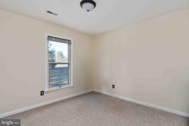 empty room with carpet, visible vents, and baseboards