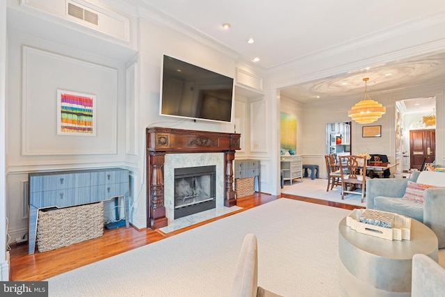 living room featuring crown molding, wood-type flooring, and a premium fireplace