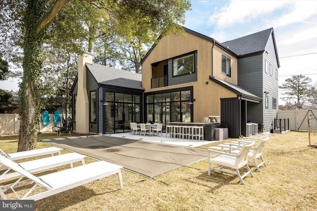 rear view of property featuring a shingled roof, a chimney, a patio area, and fence