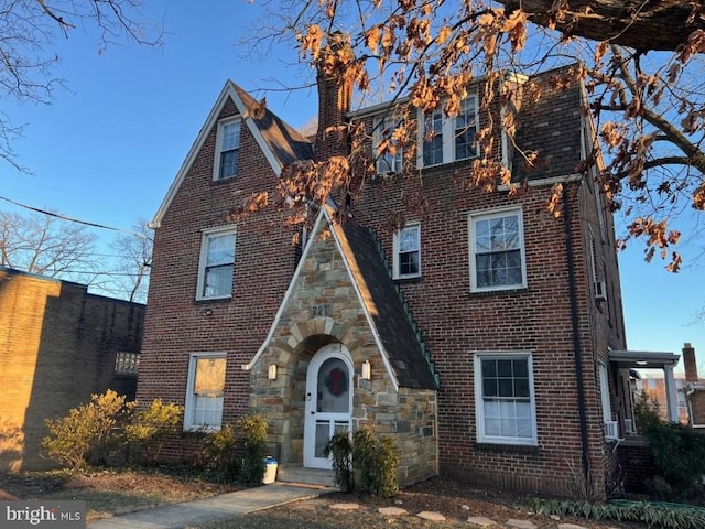 view of front facade with brick siding and a chimney