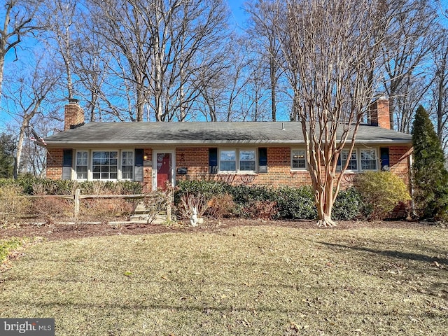 single story home with brick siding, a chimney, and a front yard