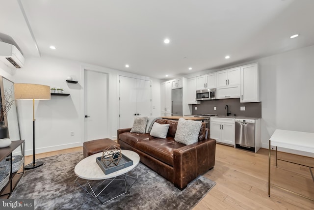 living area featuring a wall mounted AC, recessed lighting, and light wood-style floors