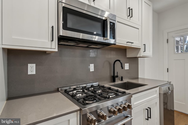 kitchen with stainless steel appliances, a sink, and white cabinets