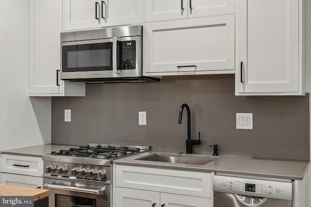 kitchen with stainless steel appliances, light countertops, a sink, and white cabinetry