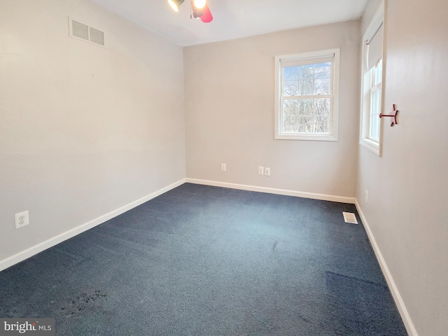 spare room with ceiling fan and dark colored carpet