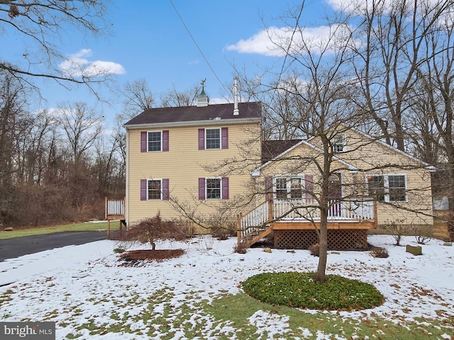 snow covered rear of property with a wooden deck