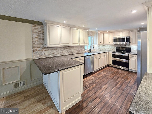 kitchen featuring sink, kitchen peninsula, stainless steel appliances, and dark hardwood / wood-style flooring