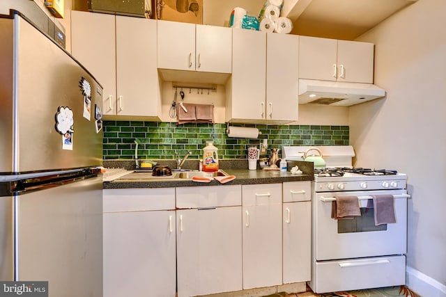 kitchen featuring white cabinets, white gas stove, stainless steel fridge, and tasteful backsplash