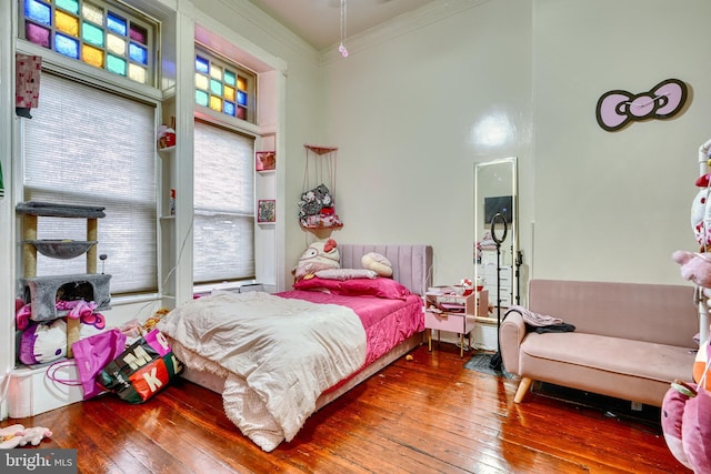 bedroom featuring hardwood / wood-style flooring, ornamental molding, and a high ceiling