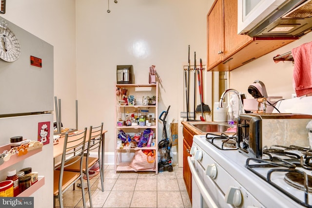 kitchen with sink, white appliances, and light tile patterned flooring