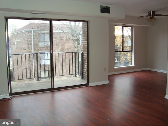 unfurnished room with a ceiling fan, wood finished floors, visible vents, and baseboards