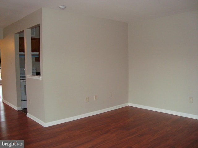 unfurnished room with dark wood-type flooring and baseboards