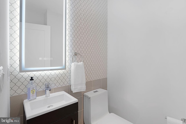 bathroom with toilet, tile walls, and vanity