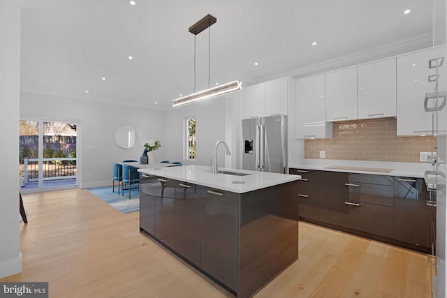 kitchen featuring hanging light fixtures, high quality fridge, light countertops, and white cabinets