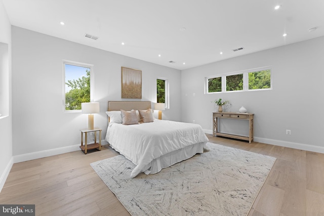 bedroom with multiple windows, light wood-type flooring, and visible vents