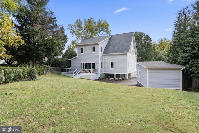 rear view of property featuring a shingled roof, an outbuilding, a yard, and a wooden deck