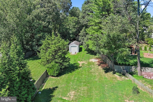 view of yard featuring a fenced backyard, an outdoor structure, and a storage shed