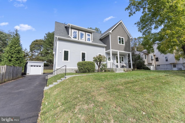 traditional-style home with a porch, an outdoor structure, fence, and a front yard