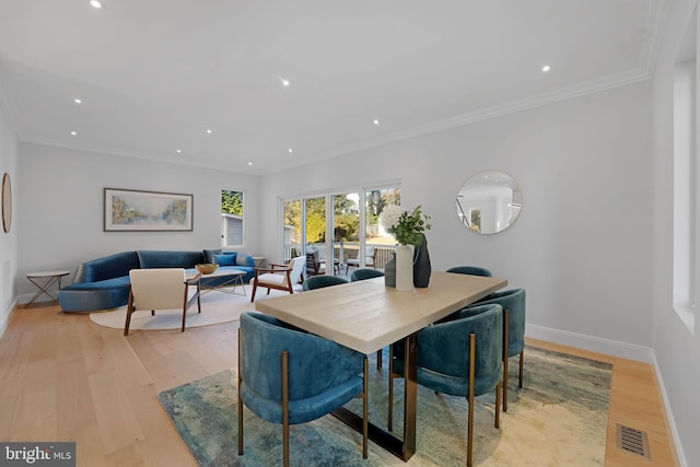 dining area with visible vents, crown molding, light wood-style flooring, and baseboards