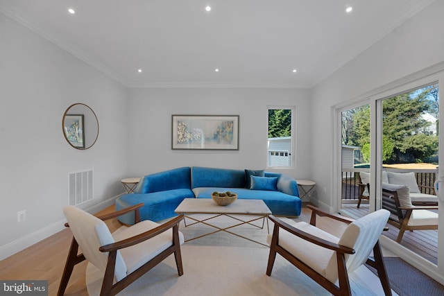 living room featuring light wood-style flooring, visible vents, baseboards, and ornamental molding