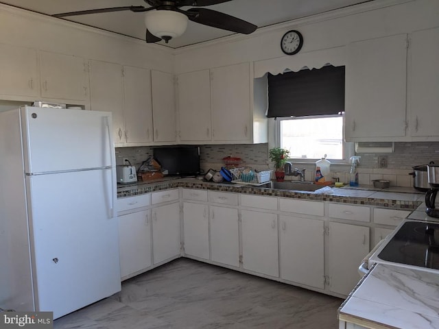 kitchen featuring marble finish floor, a sink, tasteful backsplash, freestanding refrigerator, and white cabinets