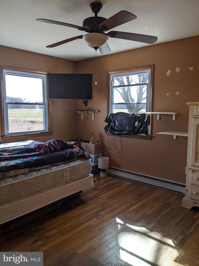 unfurnished bedroom with hardwood / wood-style flooring, a ceiling fan, and a baseboard radiator