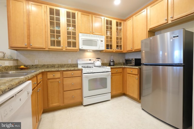 kitchen with white appliances, light stone countertops, glass insert cabinets, and tasteful backsplash