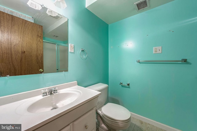 bathroom featuring toilet, vanity, and a shower with door