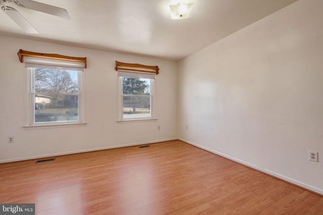 empty room with ceiling fan and light hardwood / wood-style flooring