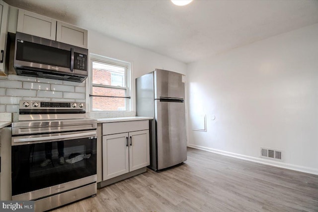 kitchen featuring gray cabinets, light hardwood / wood-style floors, and stainless steel appliances