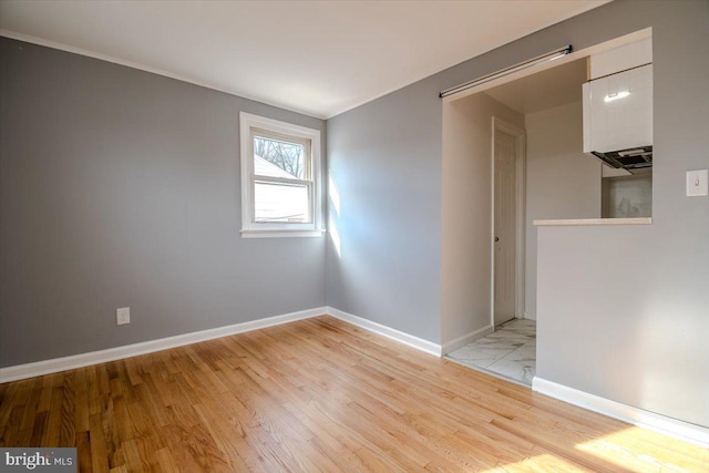 unfurnished room with light hardwood / wood-style floors and a barn door