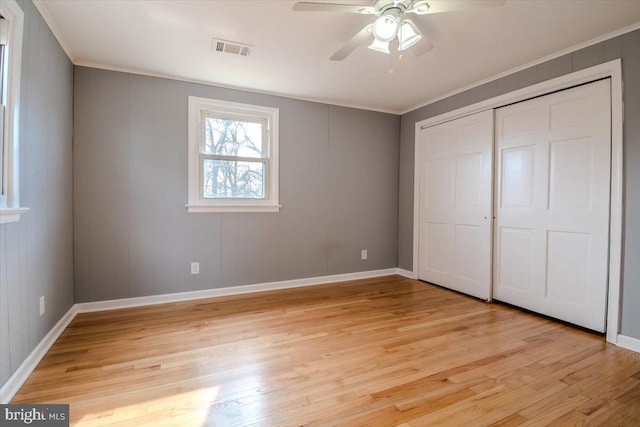 unfurnished bedroom featuring ceiling fan, a closet, crown molding, and light hardwood / wood-style floors